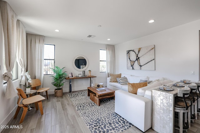 living room featuring light wood-type flooring, baseboards, visible vents, and recessed lighting