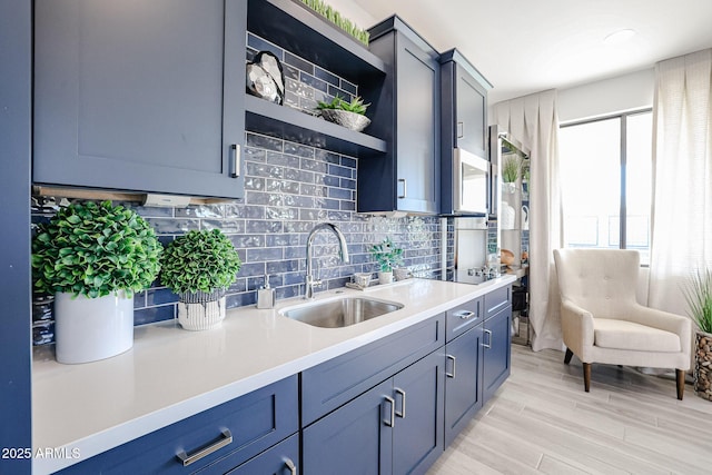 kitchen featuring tasteful backsplash, black electric cooktop, light countertops, open shelves, and a sink