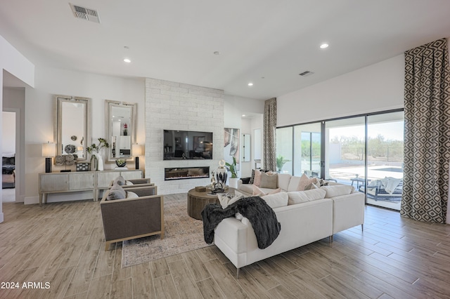 living room featuring light wood-style flooring, a fireplace, and visible vents