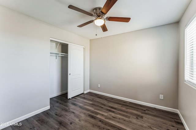 unfurnished bedroom with multiple windows, ceiling fan, a closet, and dark wood-type flooring