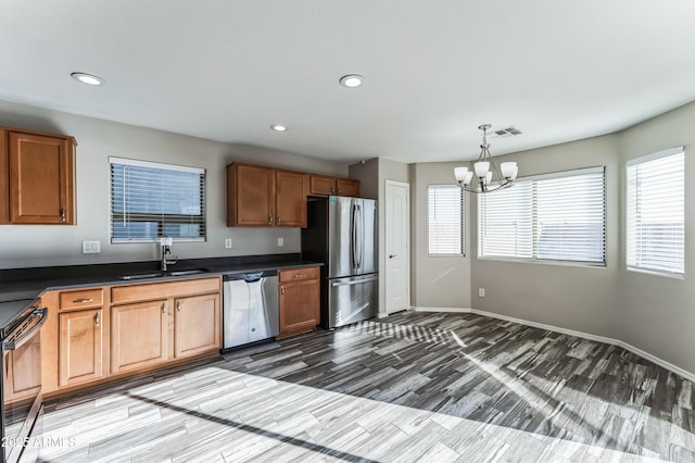 kitchen featuring sink, stainless steel appliances, a notable chandelier, decorative light fixtures, and hardwood / wood-style flooring