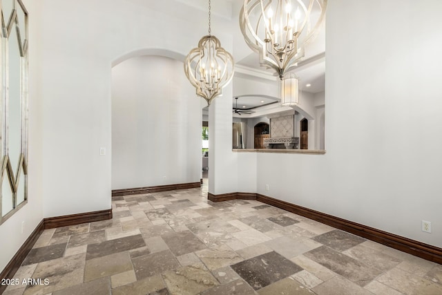 interior space with arched walkways, baseboards, a notable chandelier, and stone tile floors