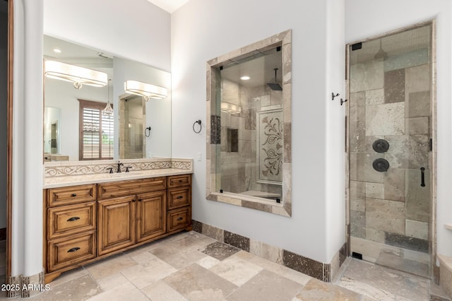 bathroom with stone tile flooring, baseboards, vanity, and a shower stall