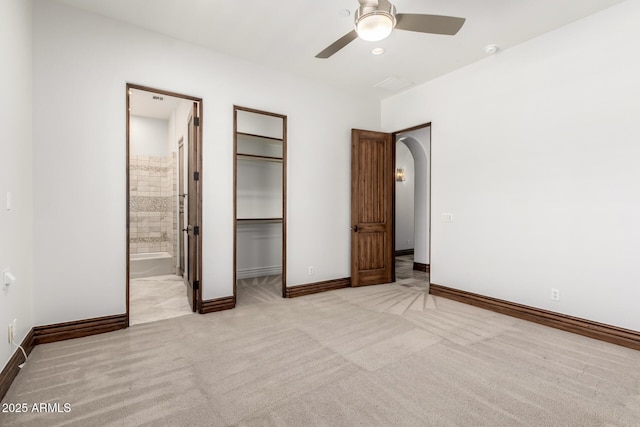 unfurnished bedroom with carpet floors, a ceiling fan, baseboards, and connected bathroom