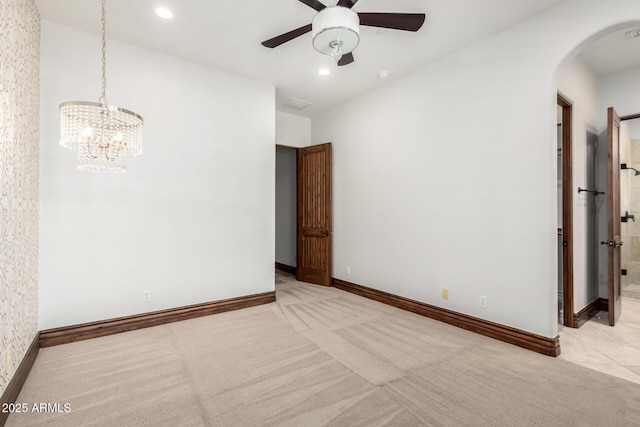 empty room featuring baseboards, arched walkways, carpet, and ceiling fan with notable chandelier