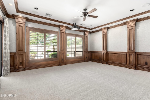 carpeted spare room with ornate columns, ceiling fan, visible vents, and ornamental molding