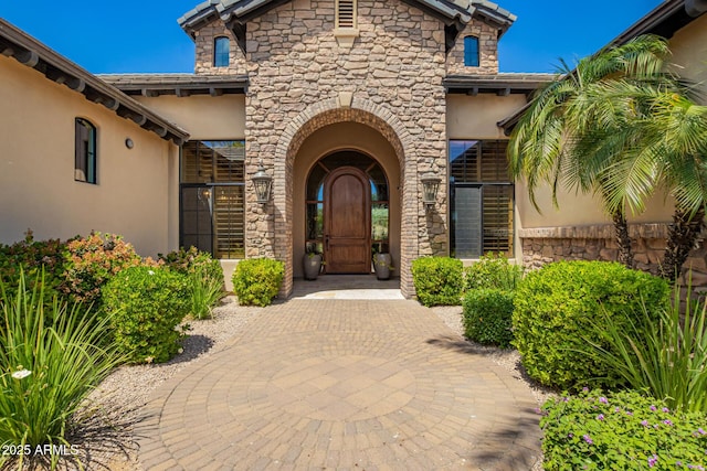 property entrance featuring stucco siding and stone siding