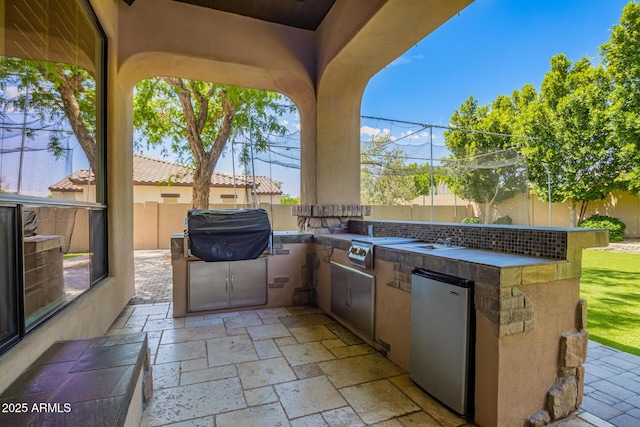 view of patio with an outdoor kitchen, a grill, and a fenced backyard