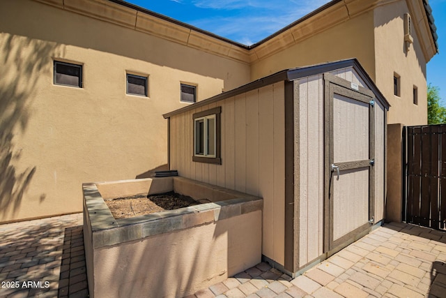 exterior space featuring a storage unit, stucco siding, and an outbuilding