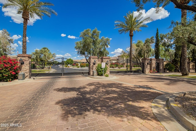 view of road with a gated entry, a gate, and curbs