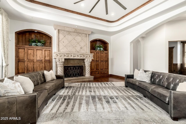 living area featuring a ceiling fan, wood finished floors, ornamental molding, a tray ceiling, and recessed lighting