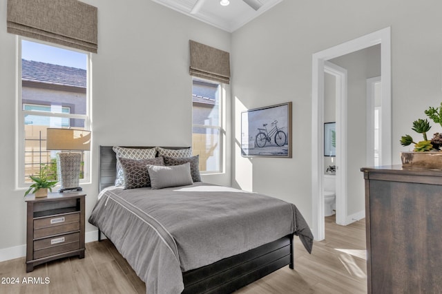 bedroom featuring ensuite bathroom, light hardwood / wood-style flooring, and crown molding