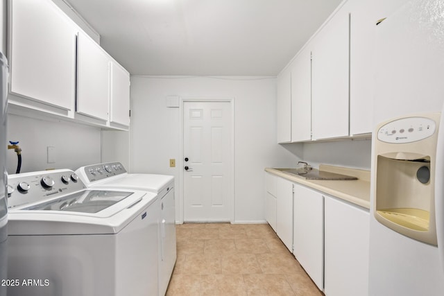 clothes washing area featuring a sink, cabinet space, light tile patterned floors, and washer and dryer