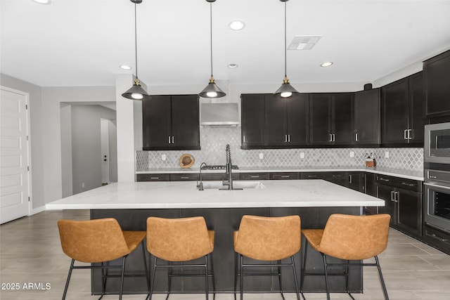 kitchen featuring stainless steel microwave, backsplash, wall chimney exhaust hood, visible vents, and wall oven