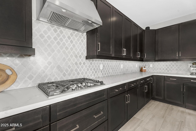 kitchen featuring stainless steel gas cooktop, wall chimney range hood, and tasteful backsplash