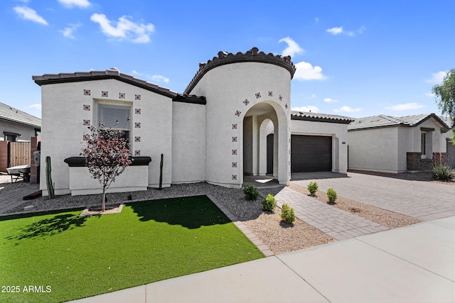mediterranean / spanish home featuring a garage, a tiled roof, decorative driveway, and stucco siding