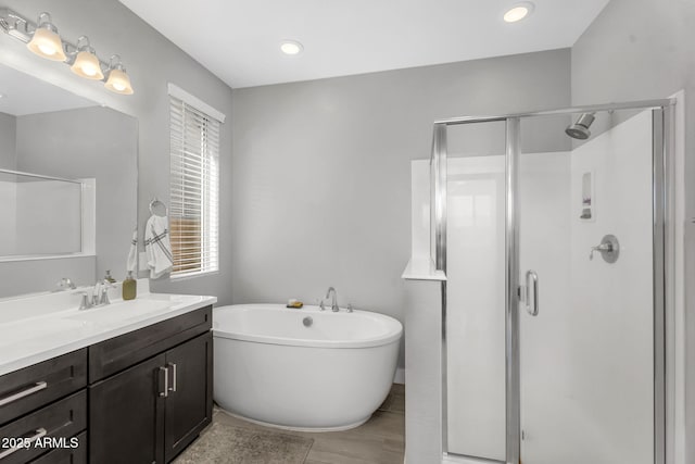 bathroom featuring a soaking tub, vanity, a stall shower, and wood finished floors