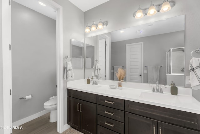 bathroom with toilet, a sink, double vanity, and baseboards