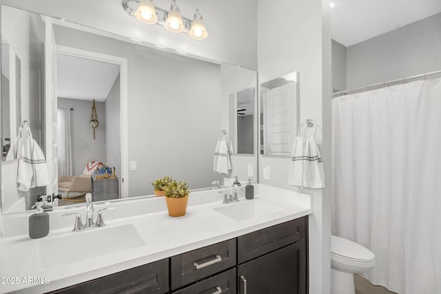 bathroom with curtained shower, double vanity, toilet, and a sink