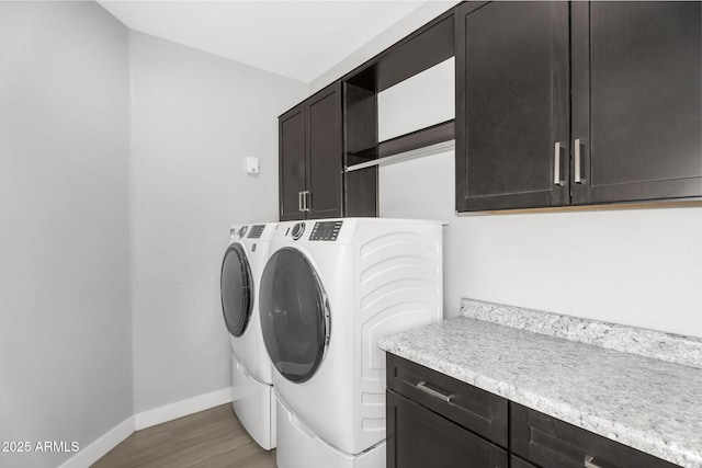 laundry area featuring baseboards, cabinet space, wood finished floors, and independent washer and dryer