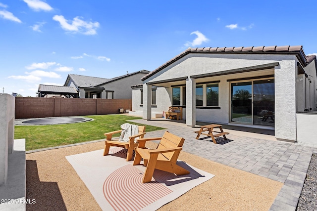 back of property with fence, a patio area, a yard, and stucco siding