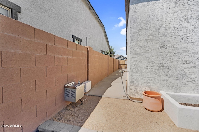 view of side of home with fence, ac unit, and stucco siding