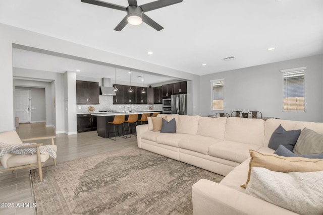 living room featuring light wood finished floors, visible vents, recessed lighting, and ceiling fan