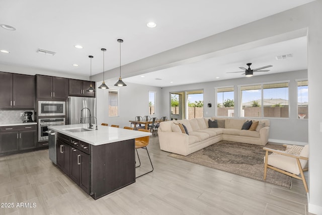 kitchen with a kitchen bar, visible vents, open floor plan, and stainless steel appliances