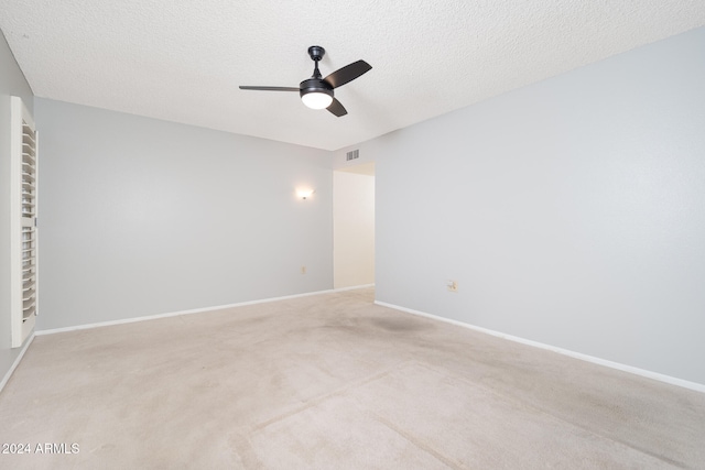 empty room with ceiling fan, a textured ceiling, and light colored carpet