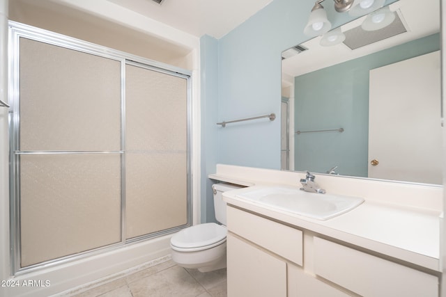 bathroom featuring a shower with door, vanity, toilet, and tile patterned floors