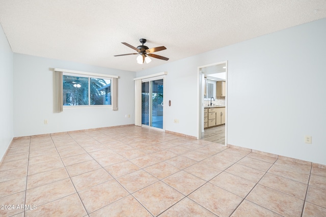 tiled empty room featuring ceiling fan, a textured ceiling, and sink