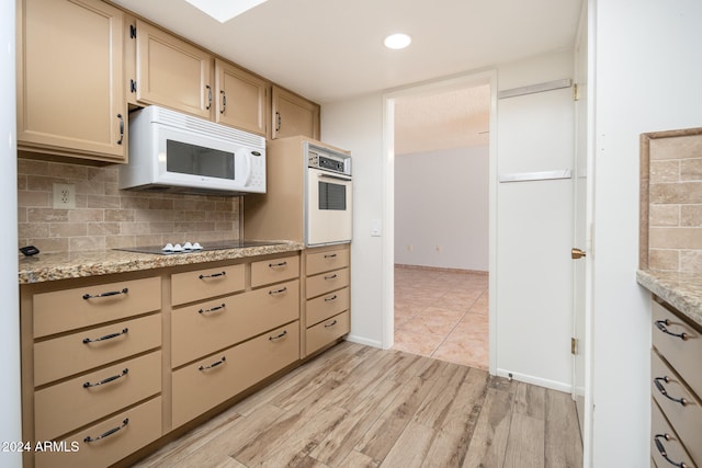 kitchen with decorative backsplash, light hardwood / wood-style floors, light stone counters, and white appliances