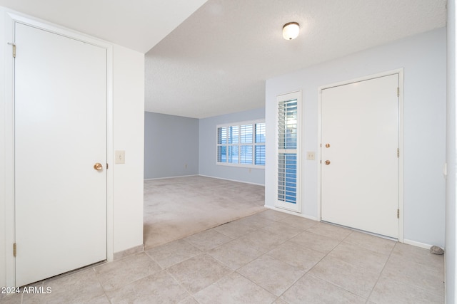 entryway featuring light carpet and a textured ceiling