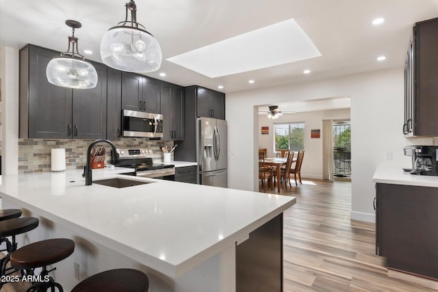 11421 W Lakeshore Dr, Youngtown, AZ 85363 - kitchen featuring light countertops, a kitchen bar, a skylight, and appliances with stainless steel finishes