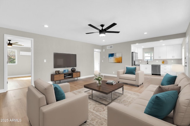 living room featuring sink, ceiling fan, and light wood-type flooring