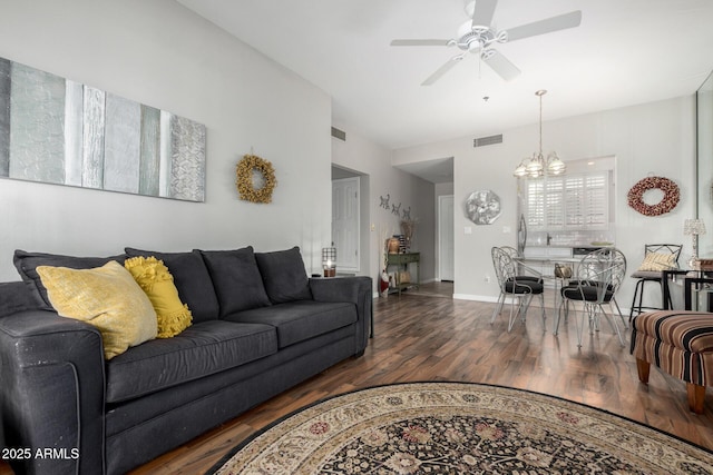 living area featuring visible vents, dark wood finished floors, baseboards, and ceiling fan with notable chandelier