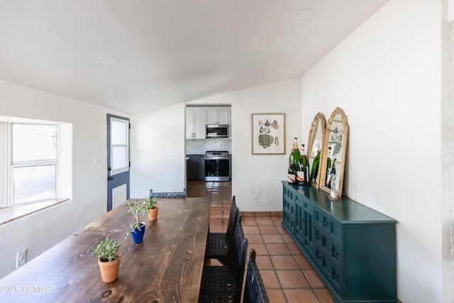 dining area featuring lofted ceiling and dark tile patterned flooring