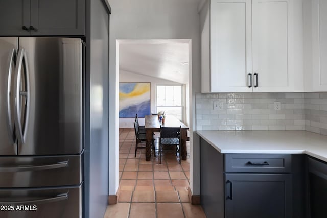 kitchen with gray cabinets, light tile patterned floors, stainless steel fridge, white cabinets, and tasteful backsplash