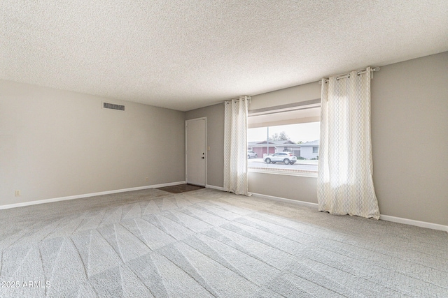 carpeted spare room featuring baseboards, visible vents, and a textured ceiling