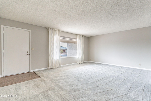 empty room with baseboards, a textured ceiling, and carpet flooring