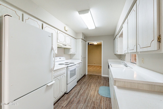 kitchen with white appliances, wood finished floors, a sink, light countertops, and under cabinet range hood