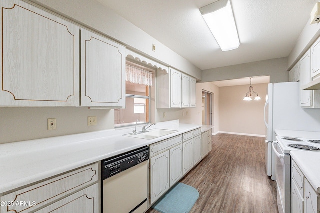 kitchen featuring white appliances, wood finished floors, an inviting chandelier, a sink, and light countertops