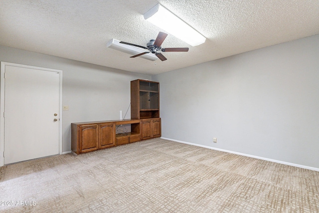 spare room featuring light colored carpet, baseboards, and ceiling fan