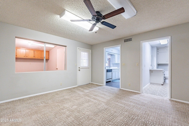 unfurnished room featuring visible vents, baseboards, ceiling fan, light colored carpet, and a textured ceiling