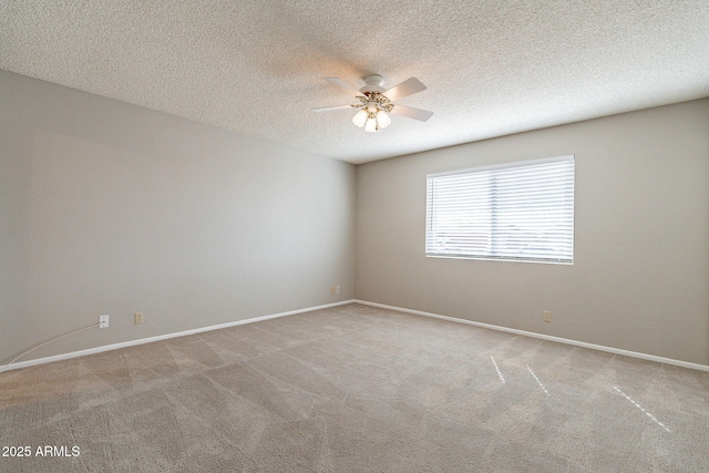 carpeted spare room with a ceiling fan, baseboards, and a textured ceiling