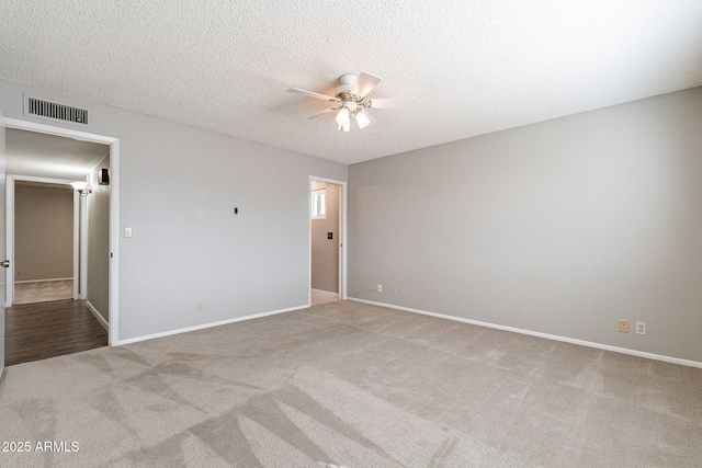 unfurnished bedroom featuring visible vents, a textured ceiling, carpet, baseboards, and ceiling fan