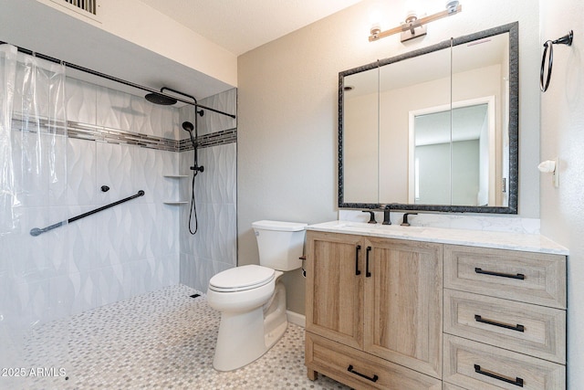 bathroom with vanity, toilet, and a tile shower