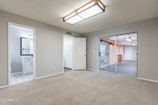 unfurnished bedroom featuring carpet flooring, baseboards, visible vents, and a textured ceiling