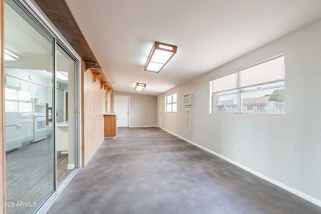 corridor with a wall mounted air conditioner, baseboards, and concrete floors