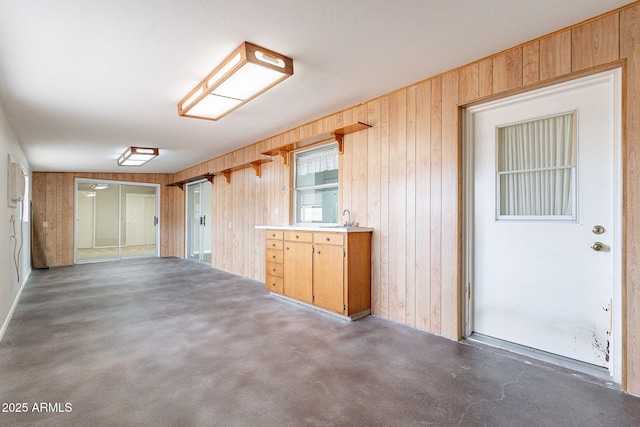 spare room with wooden walls, concrete flooring, and a sink